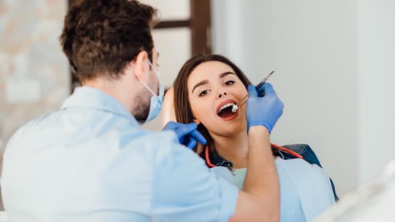 dentist making professional teeth cleaning withb cotton female young patient dental office